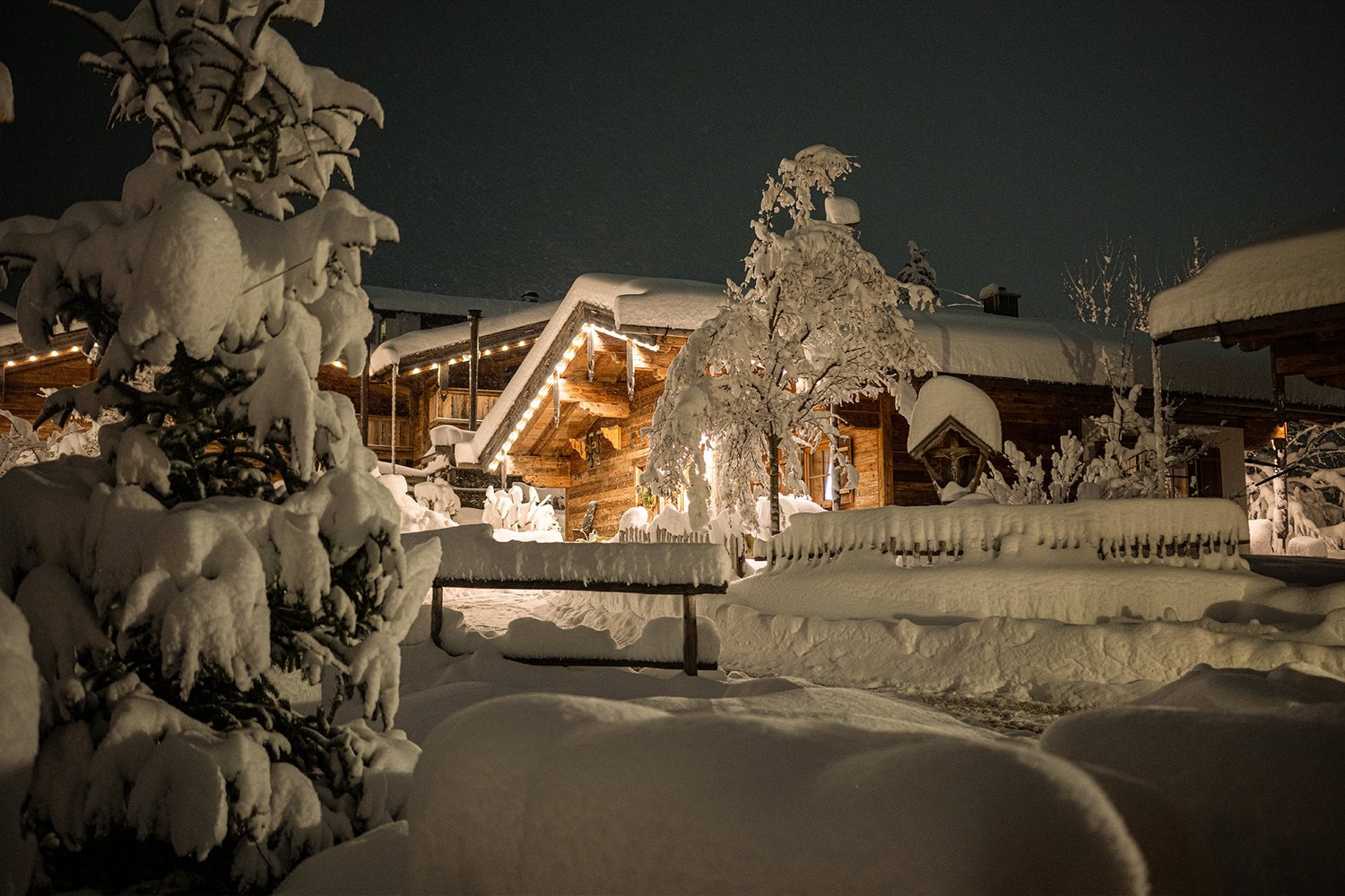 Aufnahme des verschneiten Chaletdorfs am Abend mit weihnachtlicher Beleuchtung
