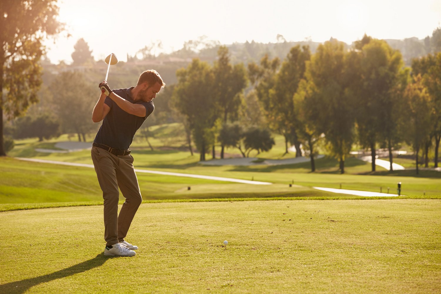 Ein Golfer schlägt einen Abschlag bei untergehender Sonne
