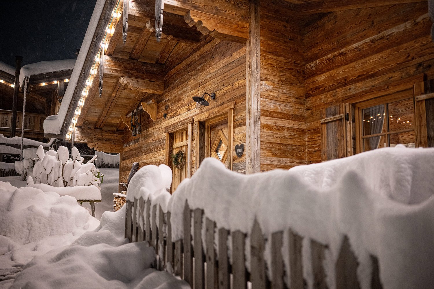 Aufnahme des verschneiten Chaletdorfs am Abend mit weihnachtlicher Beleuchtung