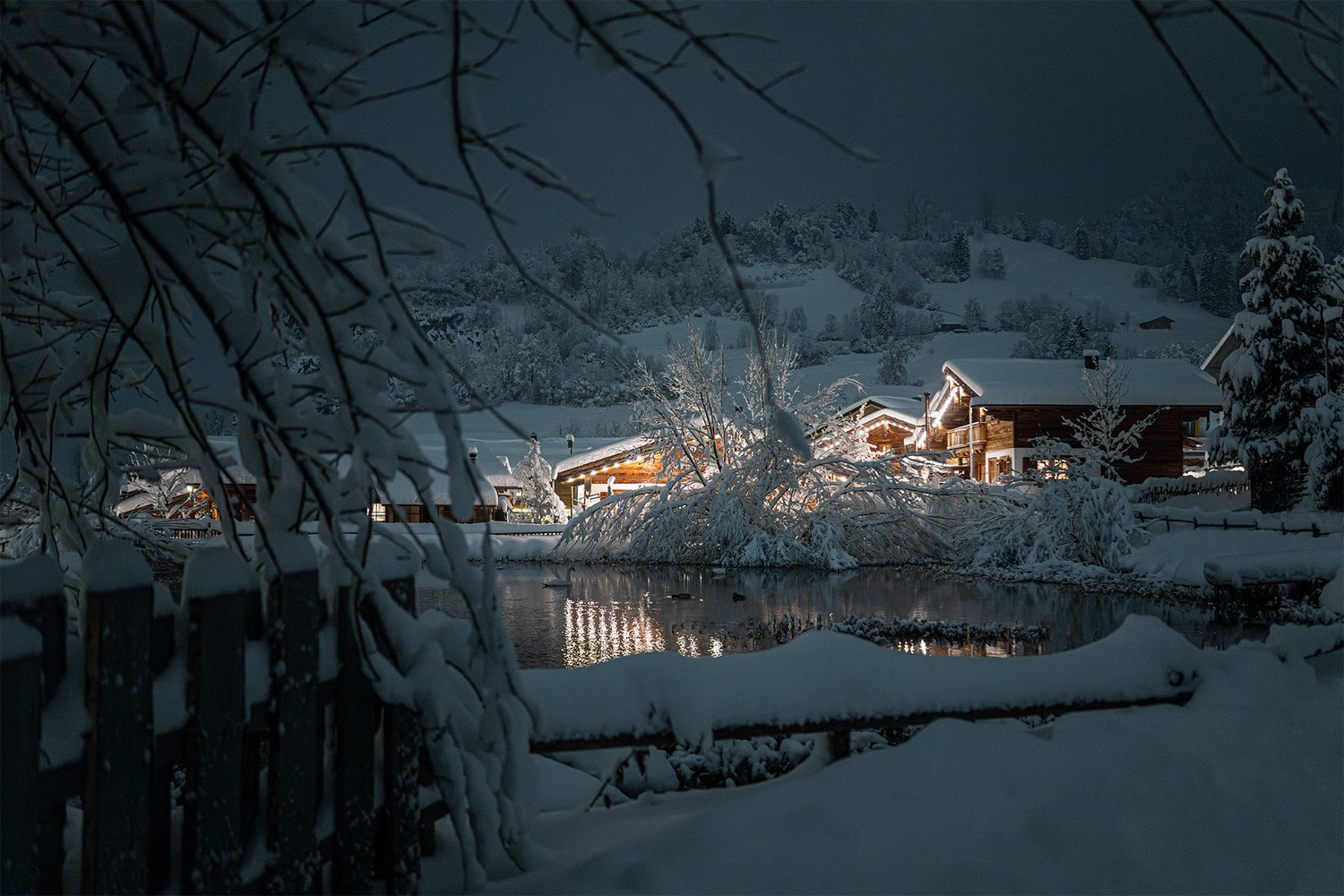 Aufnahme des verschneiten Chaletdorfs am Abend mit weihnachtlicher Beleuchtung