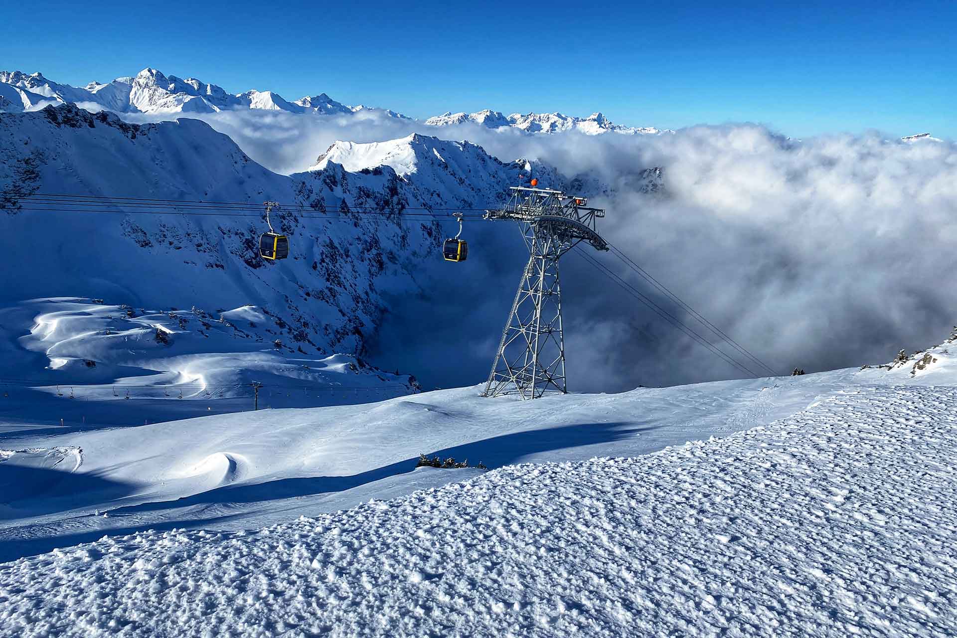 winterliche Aufnahme der Nebelhornbahn mit verschneiten Bergen im Hintergrund