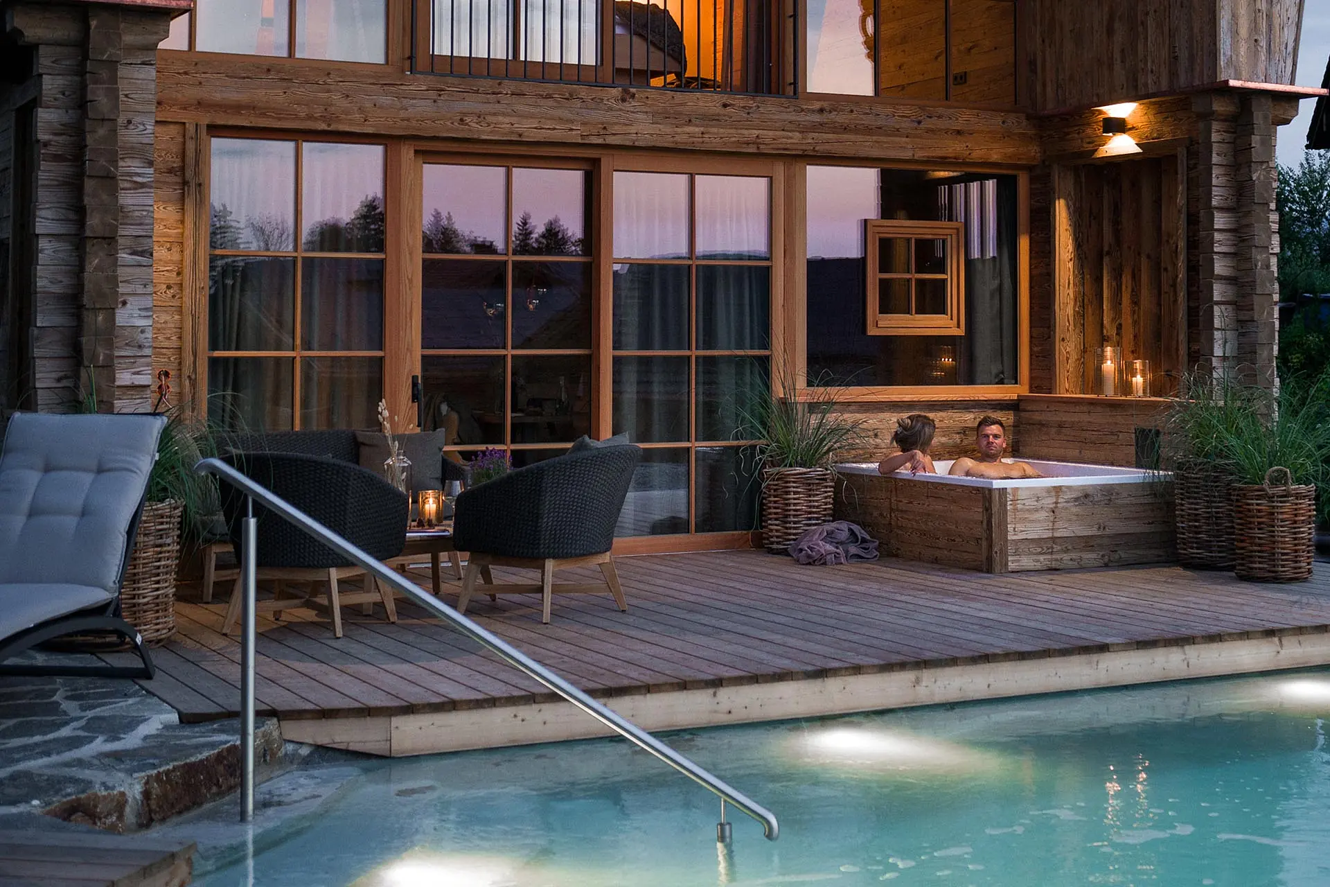 Das Premium Plus Chalet im Abendlicht und beleuchtetem Naturbadesee