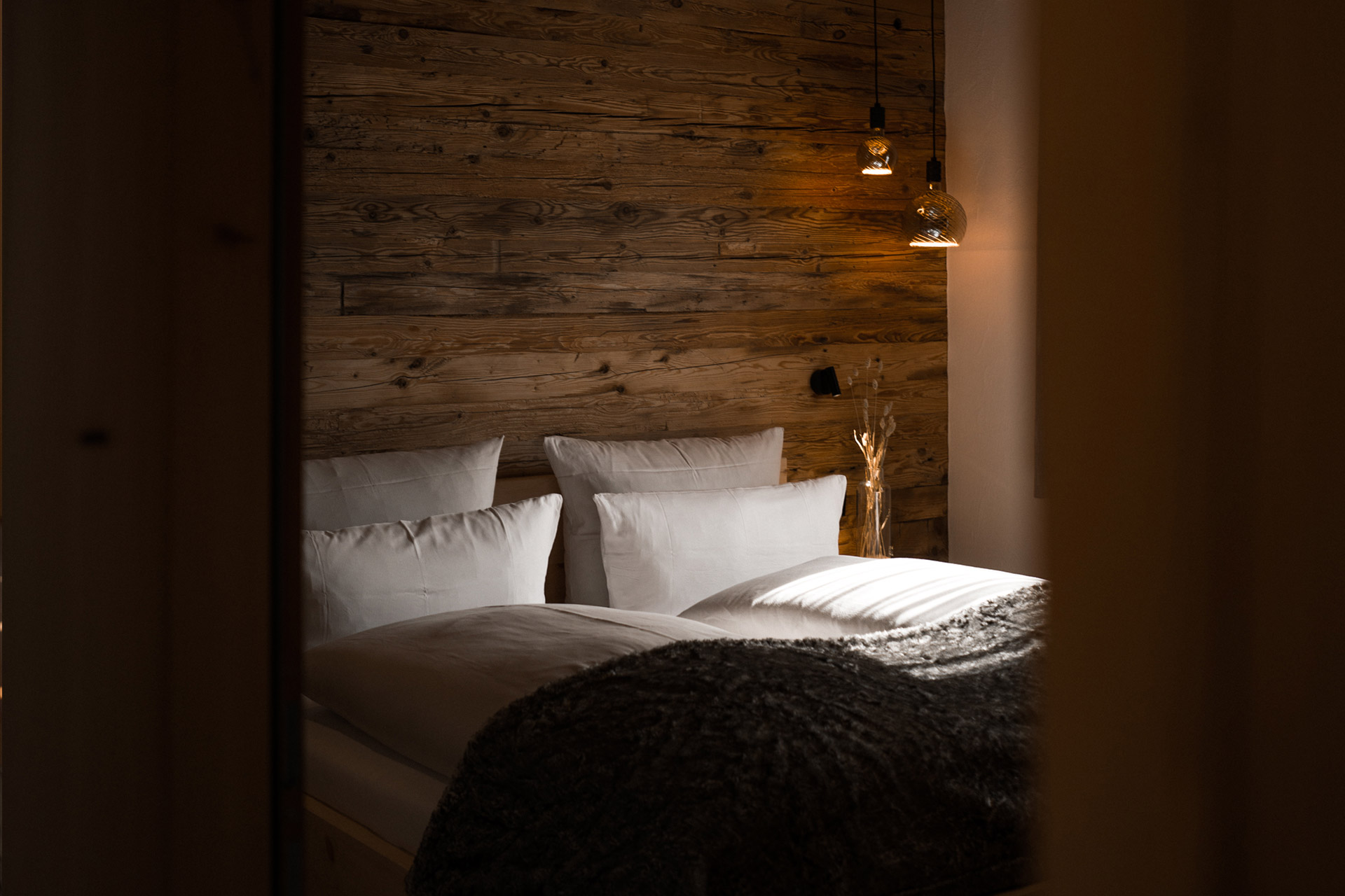 Romantisches Schlafzimmer mit weißer Bettwäsche und Lampen eines Chalets
