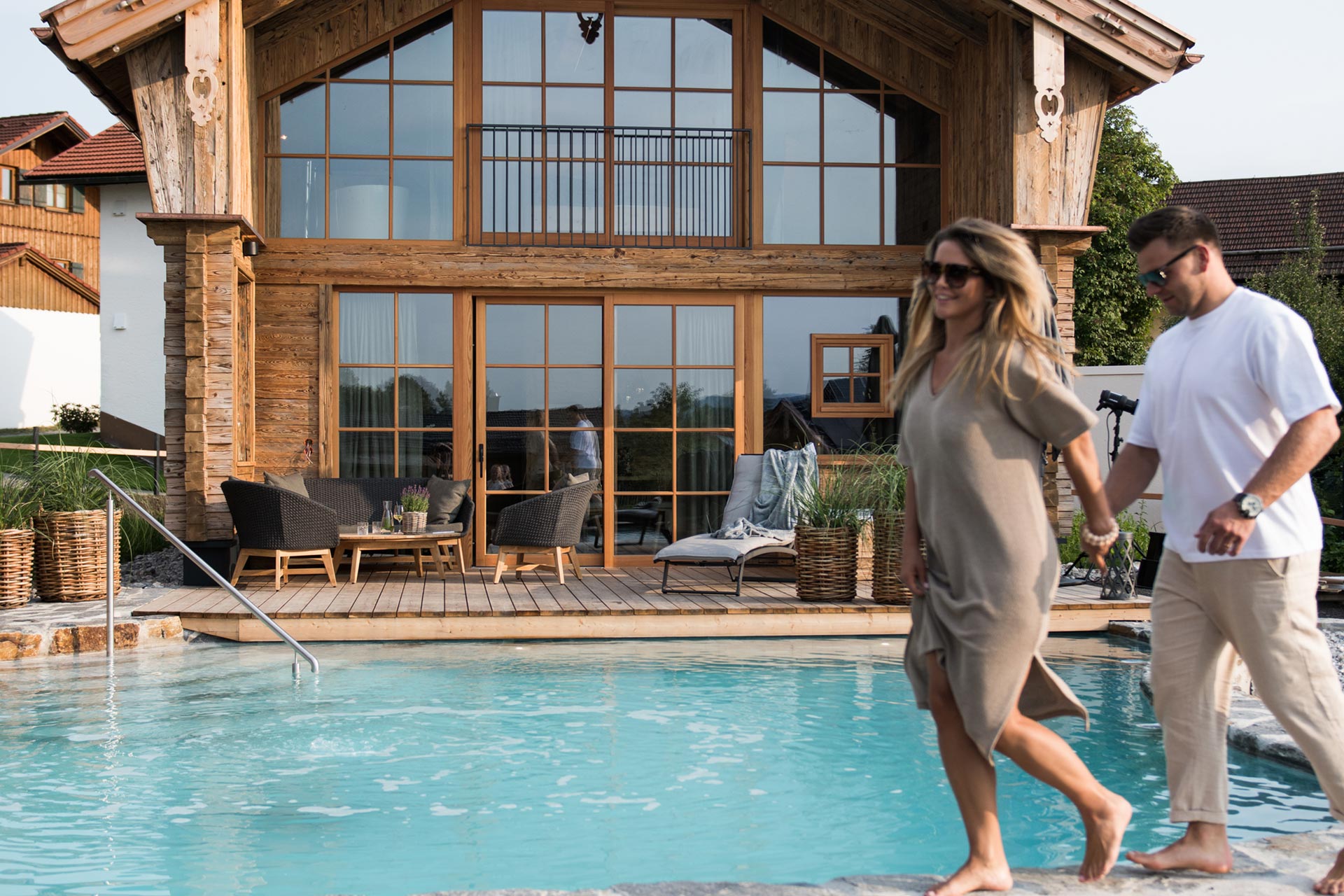 Paar läuft vor privatem Naturbadesee des Premium Plus Chalets