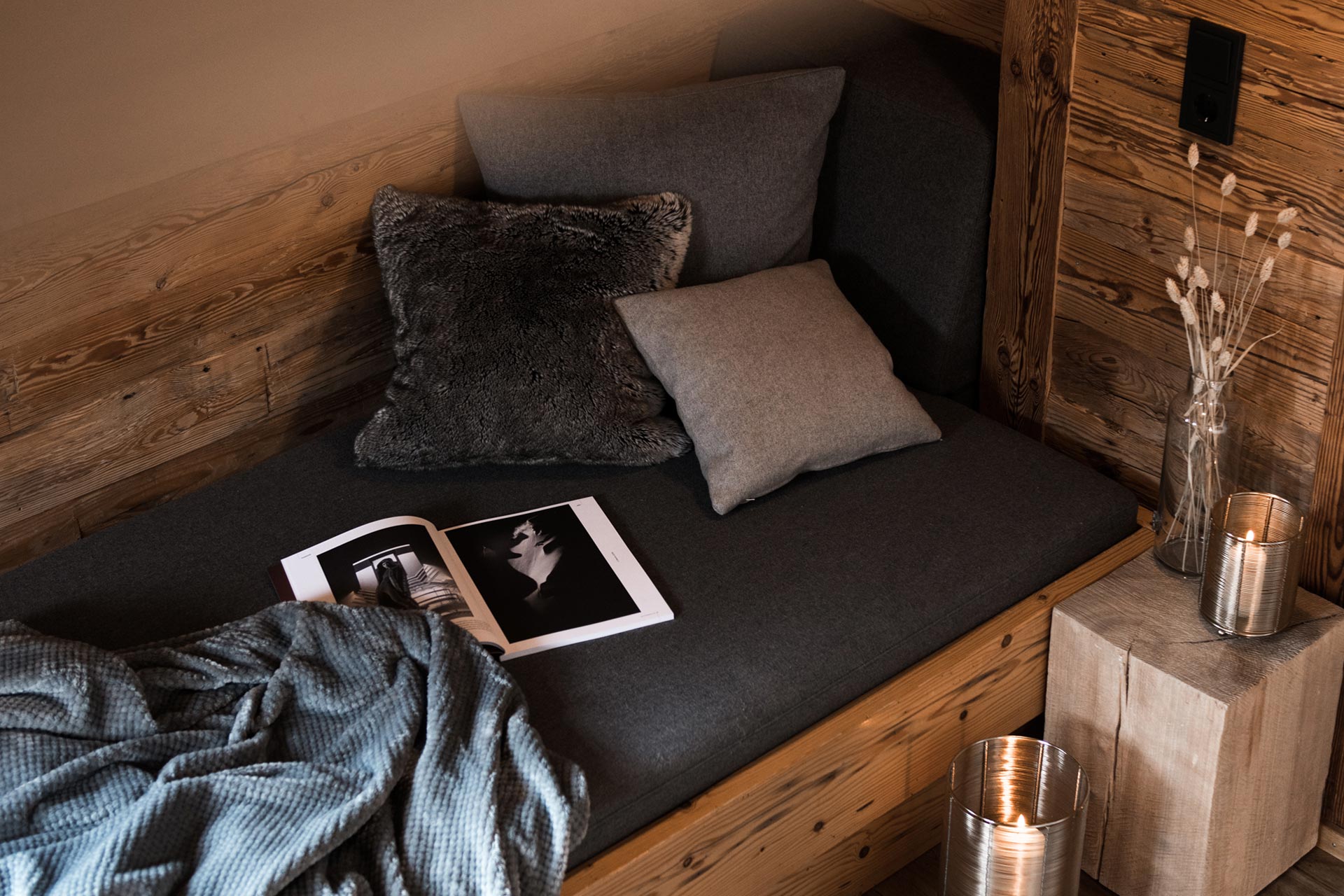 Gemütliche Sofaacke mit Blumen, Kerzen, Decke, Kissen un deiner Zeitschrift im Chalet