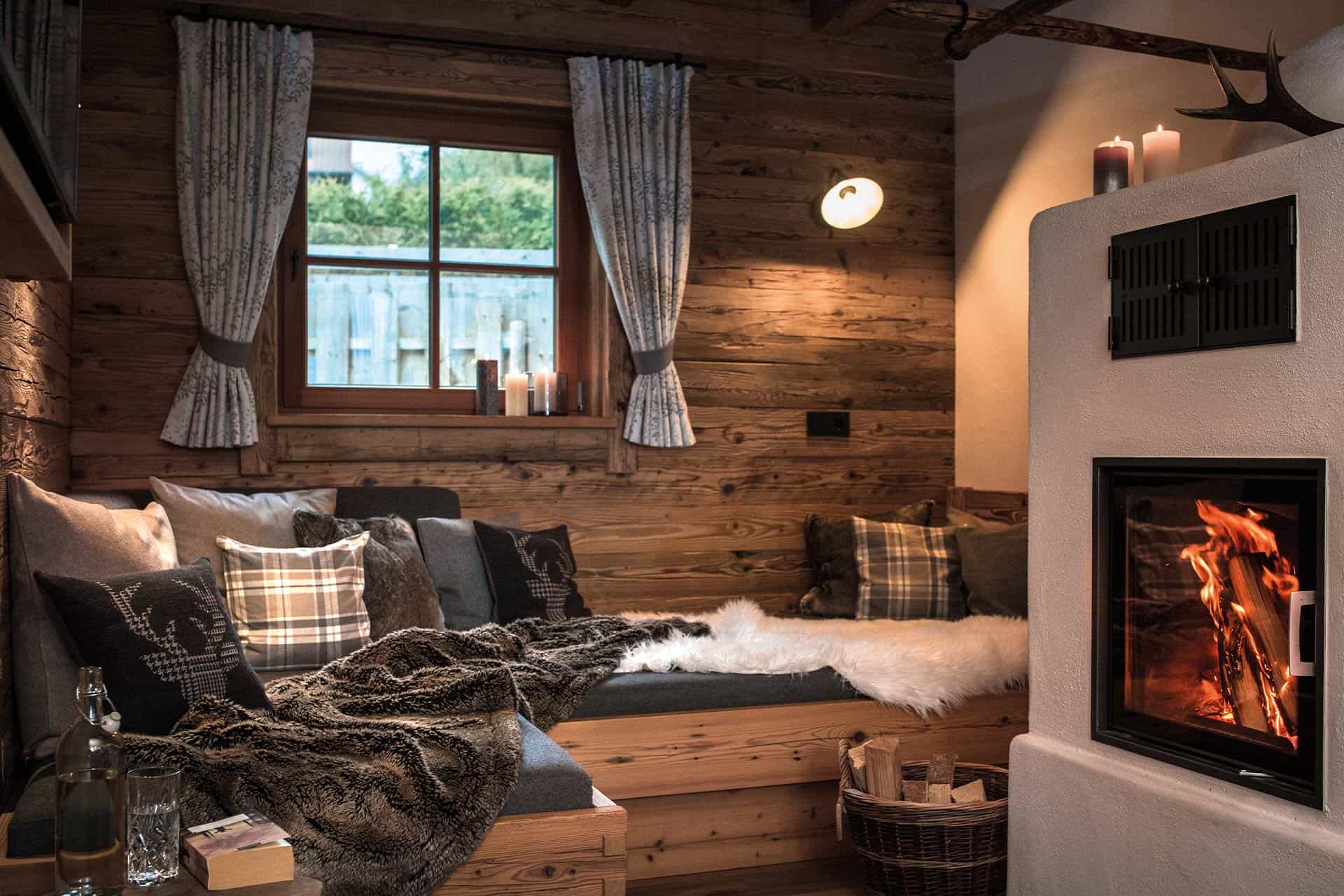 Wohnbereich mit brennendem Kamin und gemütlichem Sofa in einem Premiumchalet