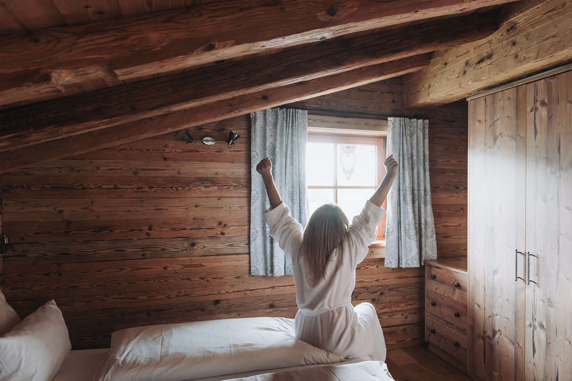 Eine Frau streckt sich nach dem Aufstehen aus dem Bett