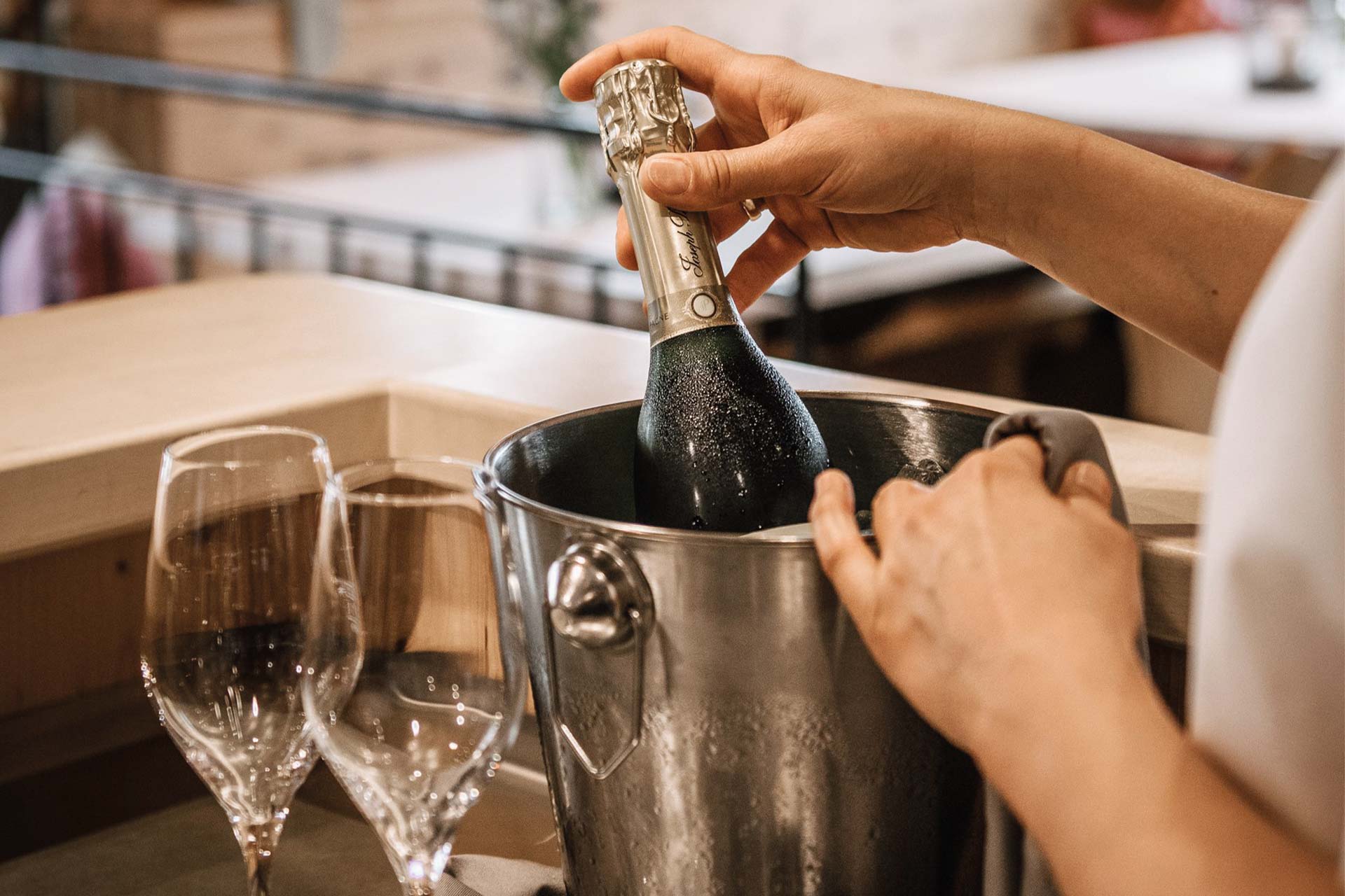Detailaufnahme einer Sektflasche im Sektkühler mit zwei Gläsern daneben