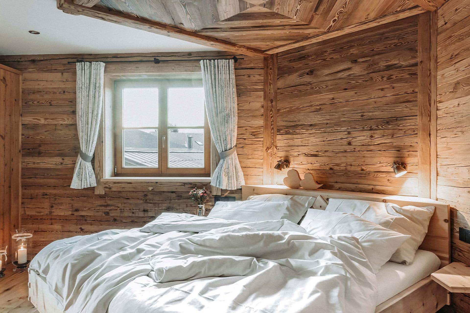 gemütliches Doppelbett mit Altholzwänden in der Ferienwohnung Mittag
