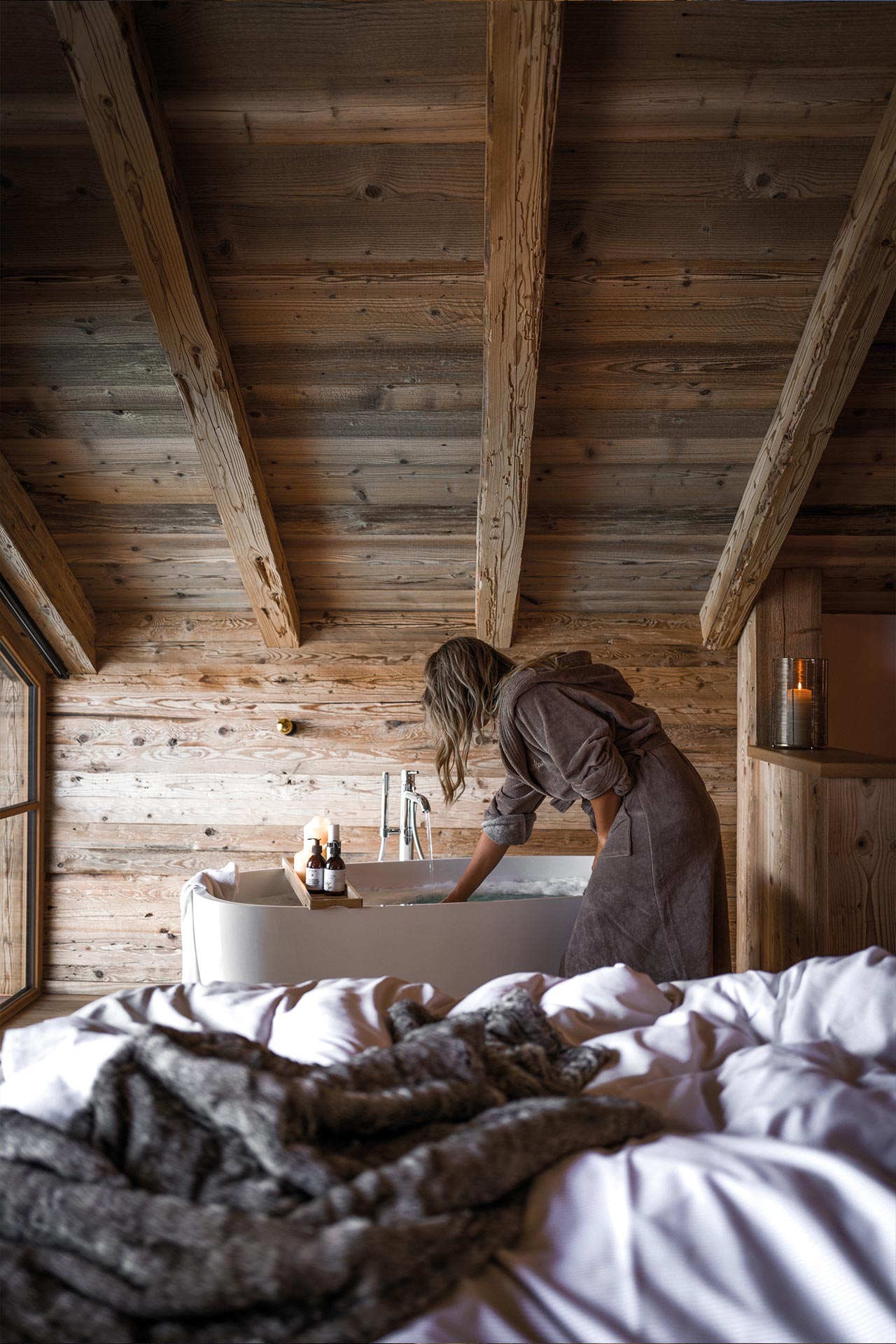 Schlafzimmer des Chalets mit Bett und freistehender Badewanne