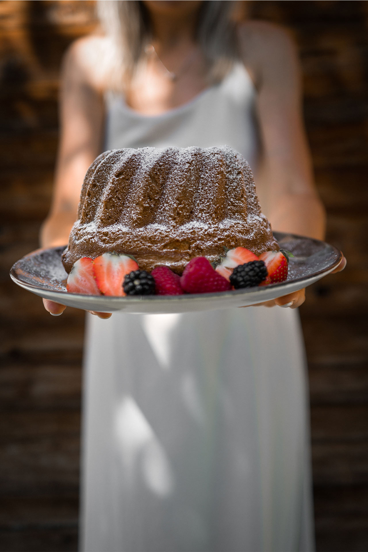Eine junge Frau hält einen Gugelhupfkuchen in der Hand