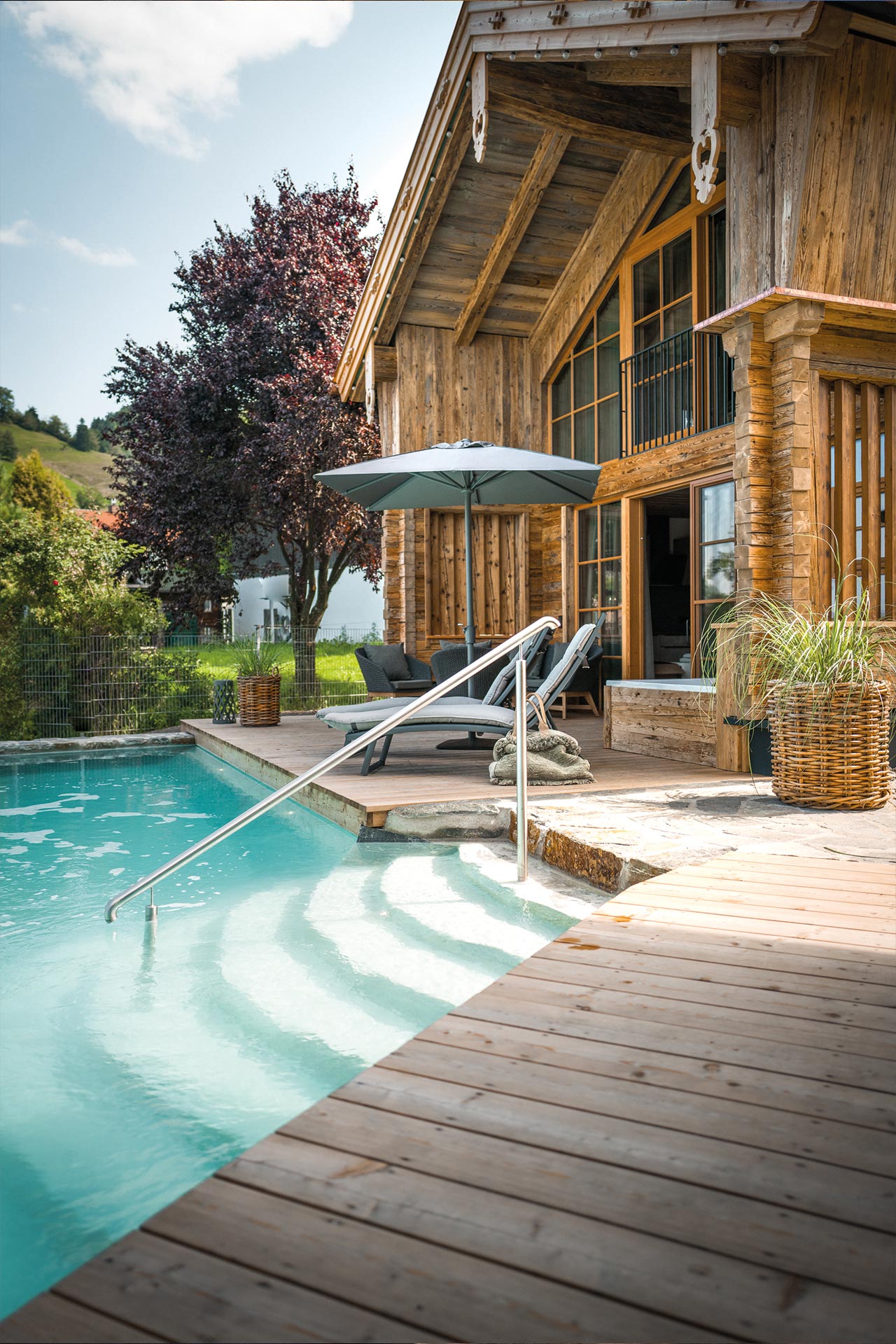 Blick auf die Chaletterrasse des Premium Plus Chalets mit privatem Naturbadesee und Whirlwanne