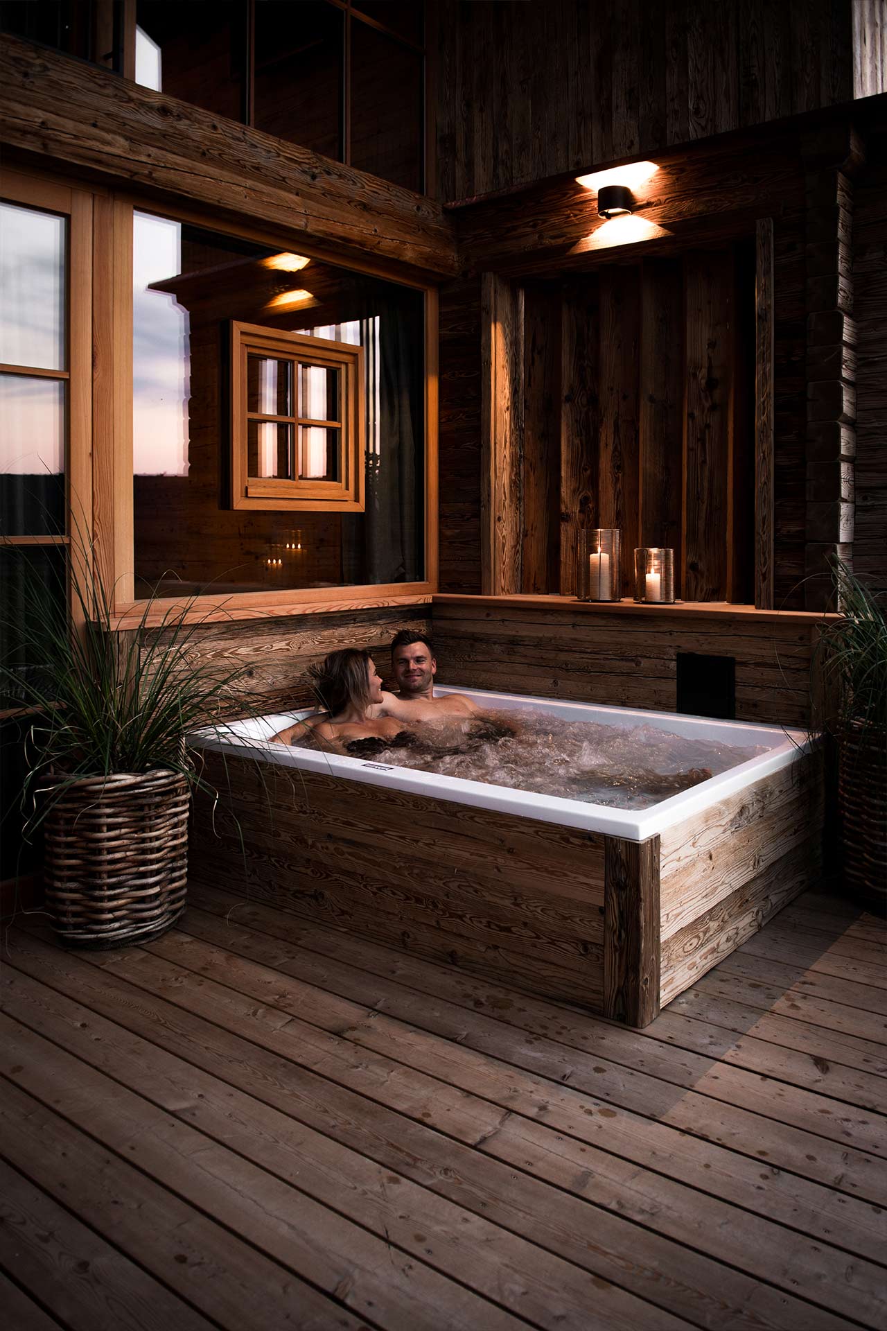 ein Pärchen genießt den Abend in ihrer privaten Whirlwanne auf der Chaletterrasse