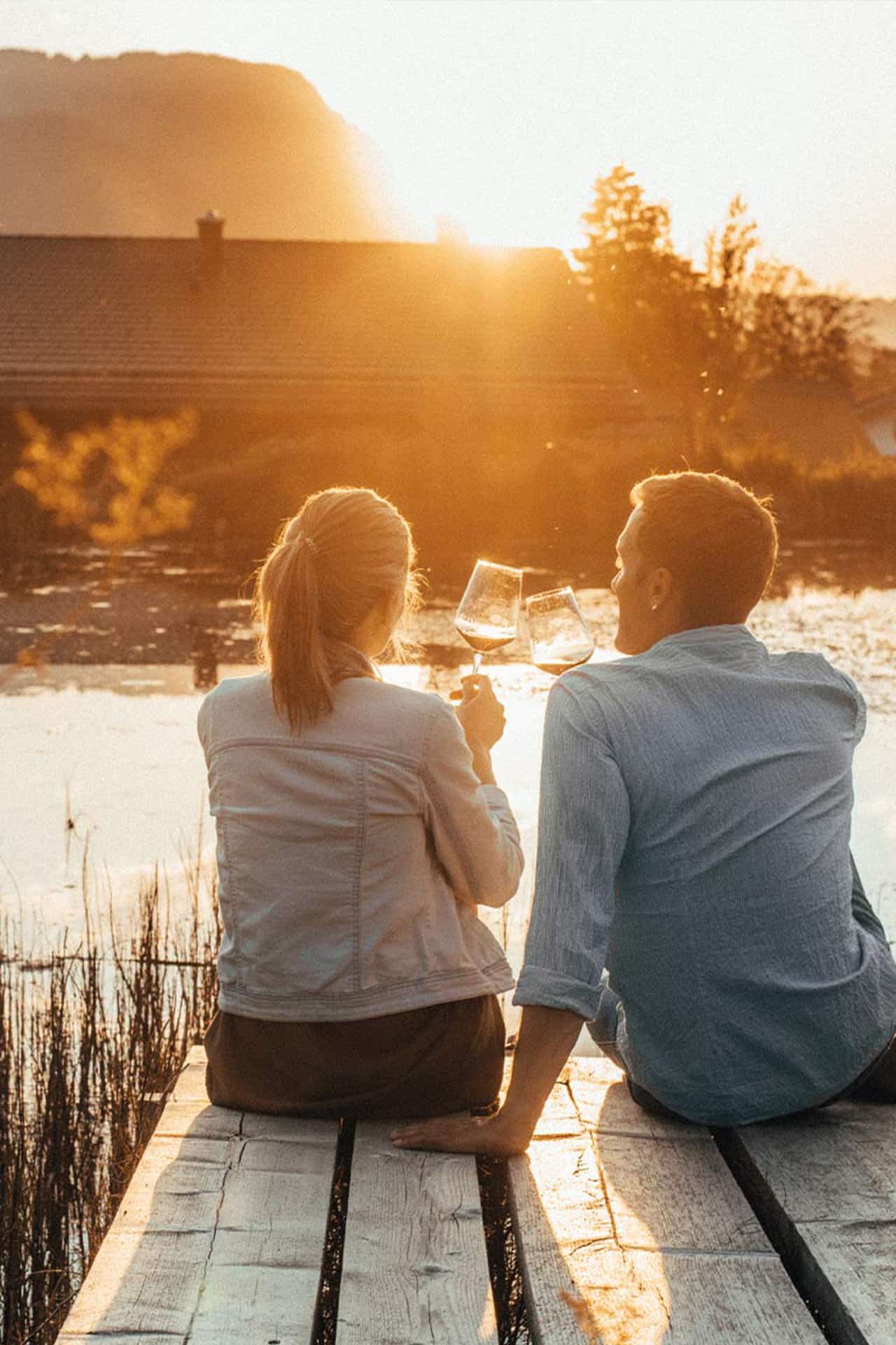 Ein Paar sitzt in der Abendsonne auf dem Steeg des Mühlweihers und trinkt einen Wein