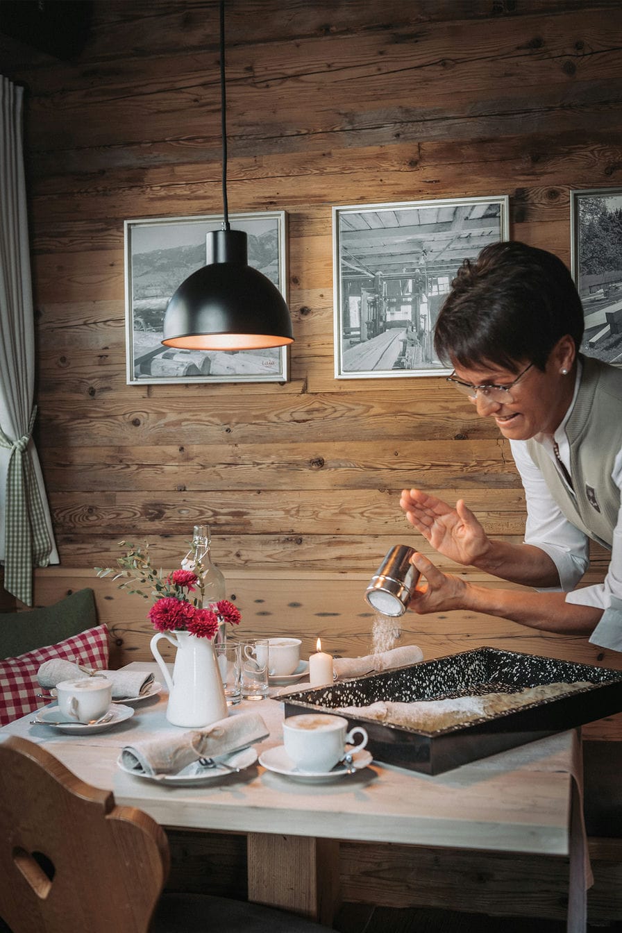 Eine Angestellte der Alpzitt Chalets bestreut einen frisch gebackenen Apfelstrudel mit Puderzucker