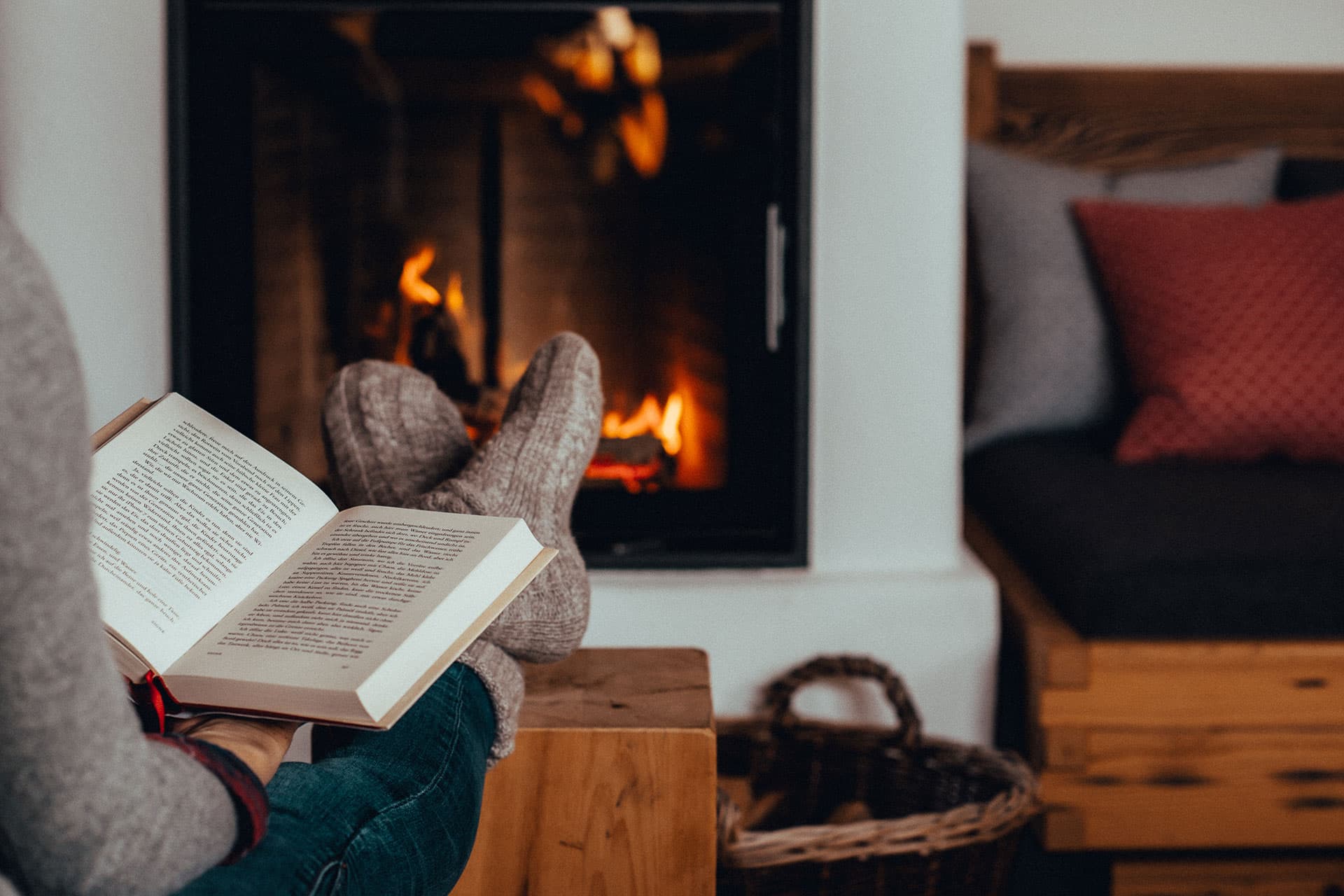 Eine Frau liest ein Buch vor Ihrem Kachelofen