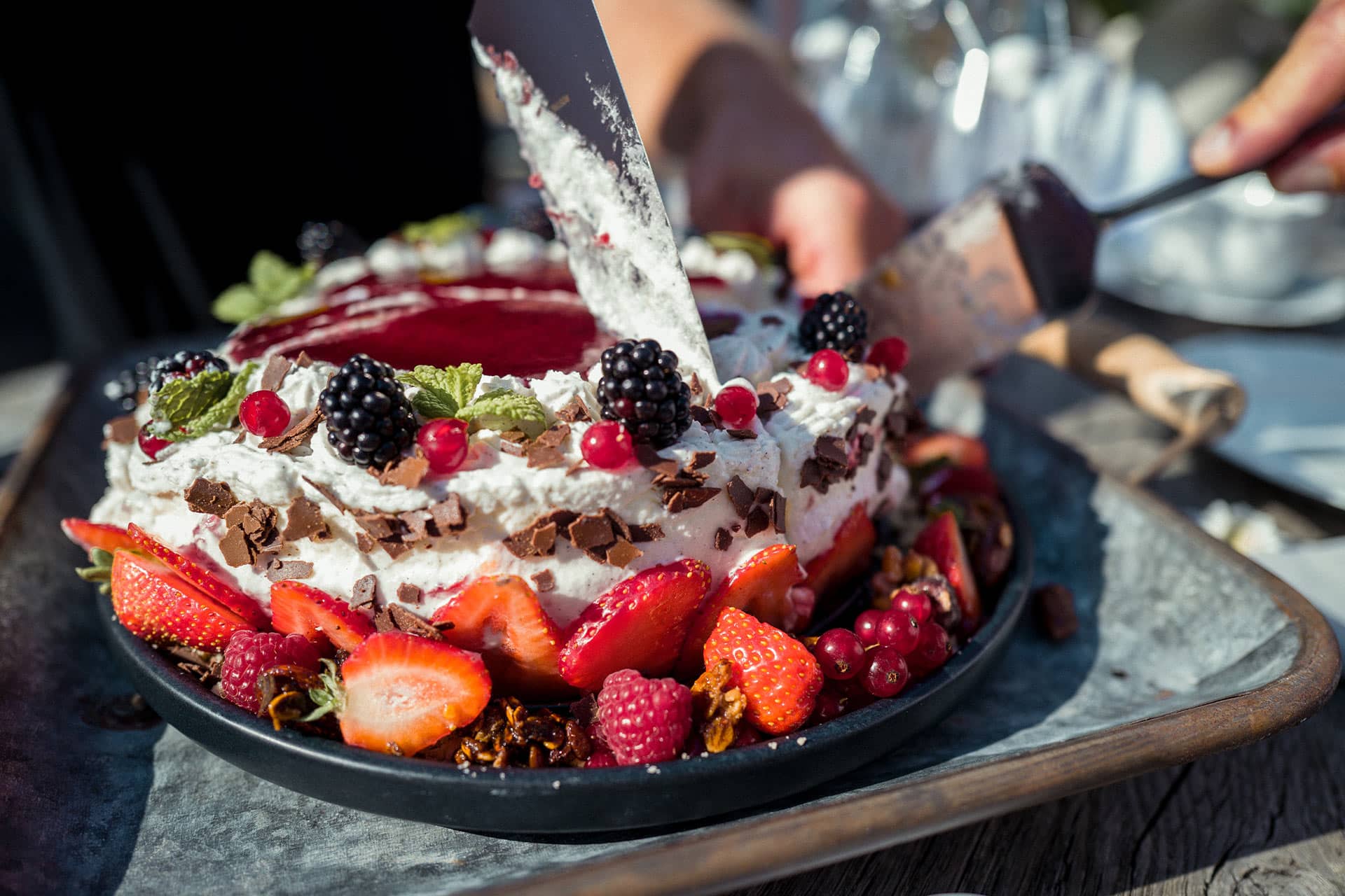 Bild einer frischen Beerentorte auf einem sommerlich gedeckten Tisch auf Alpzitts Sonnenterrasse