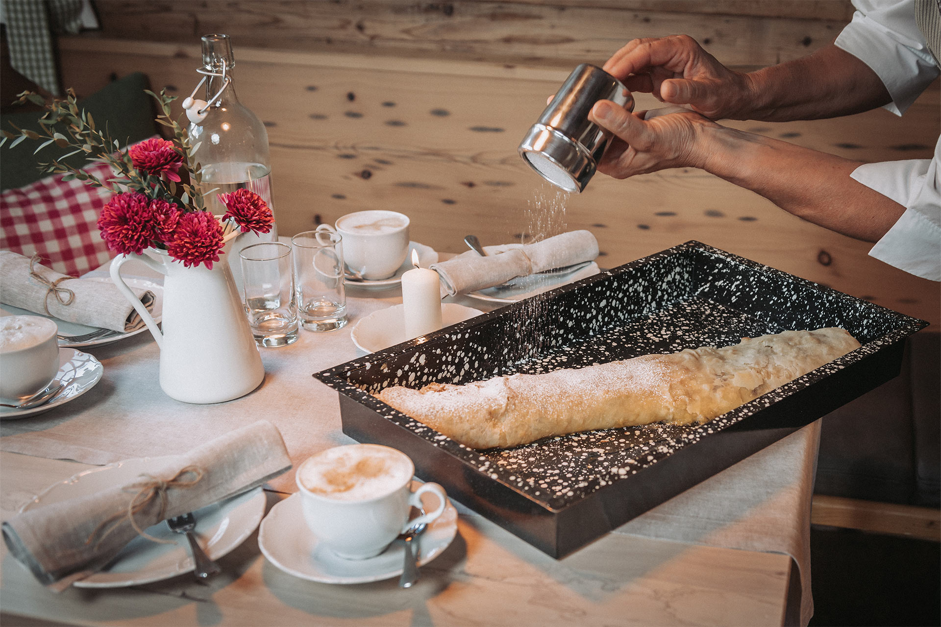Aufnahme eines frischen Apfelstrudels mit Puderzucker auf einem eingedeckten Tisch
