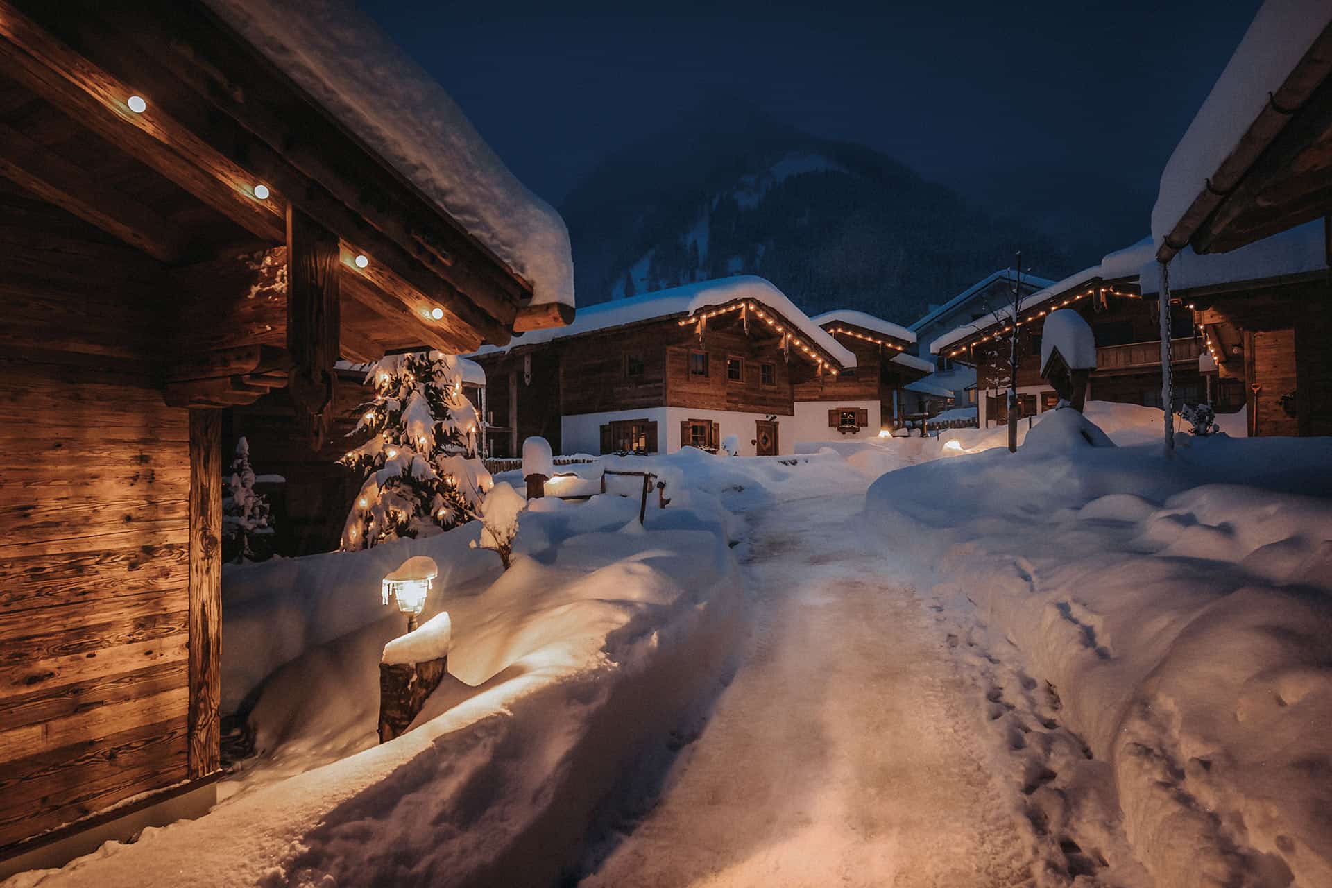 Ansicht des winterlich verschneiten Chaletdorfs am Abend mit weihnachtlicher Beleuchtung