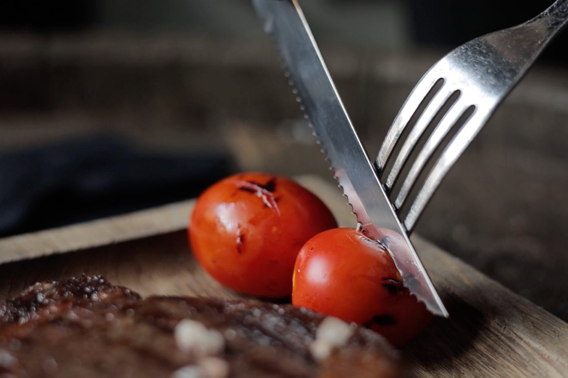 Detailaufnahme eines Bestecks, dass gerade eine Tomate schneidet