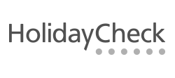 Text reads "HolidayCheck" in a simple, modern font. Below the text, there are several gray dots, likely indicating a loading or progress feature. The overall design is clean and minimalistic, emphasizing the brand name.